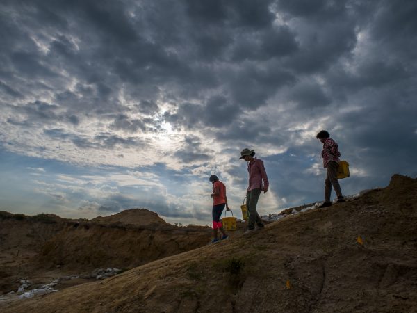 people walking into dig site with buckets
