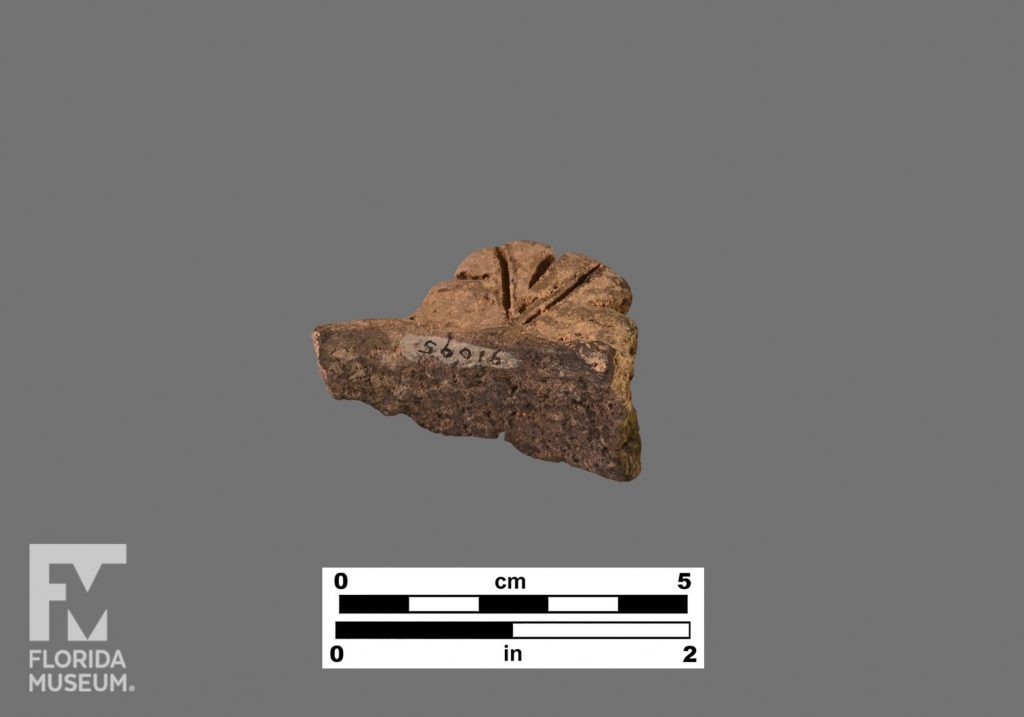 Formal artifact photo of a rectangular tab or lug handle with geometric incising