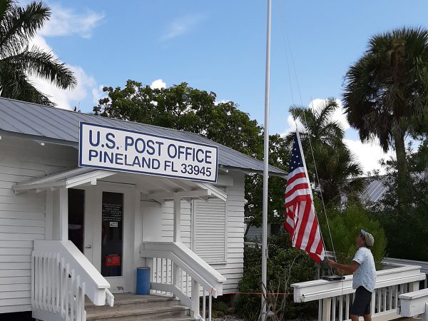 Andy Jendrusiak, RRC Groundskeeper, raises the flag outside the Pineland Post Office.