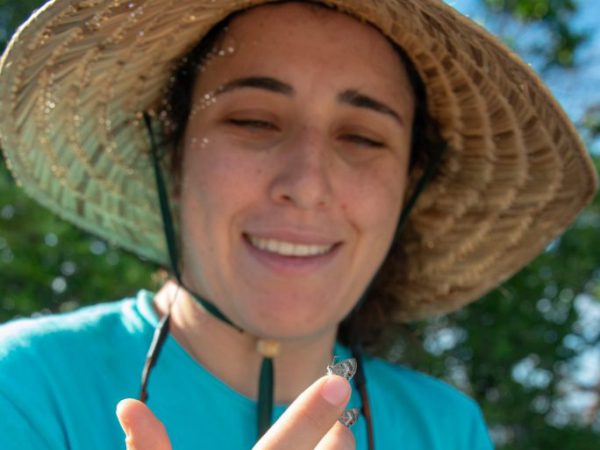 Woman in a sunhat with a butterfly perching on her finger.